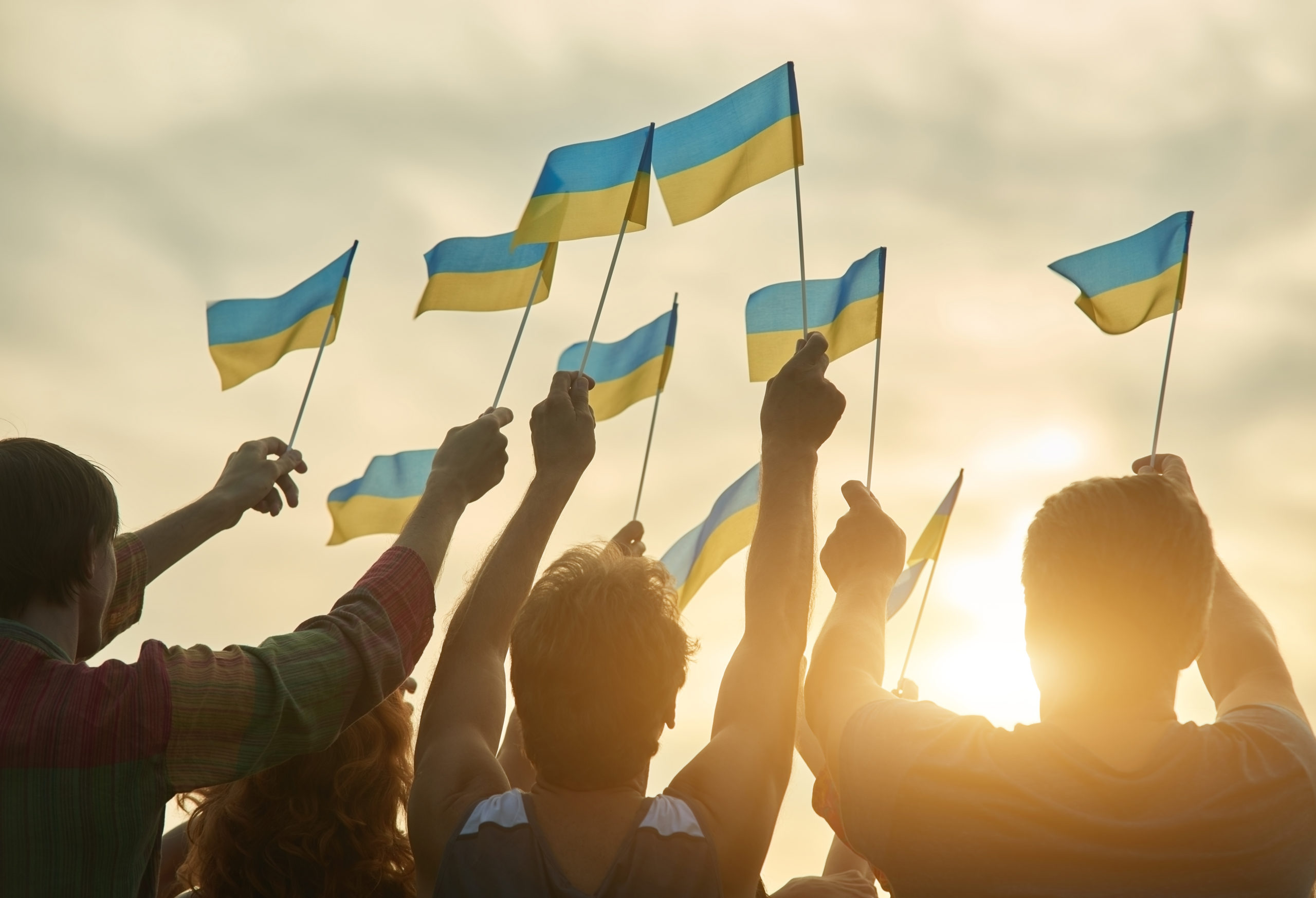 Crowd with ukrainian flags in the evening. Ukrainian revolution. Evening sunny sky background.