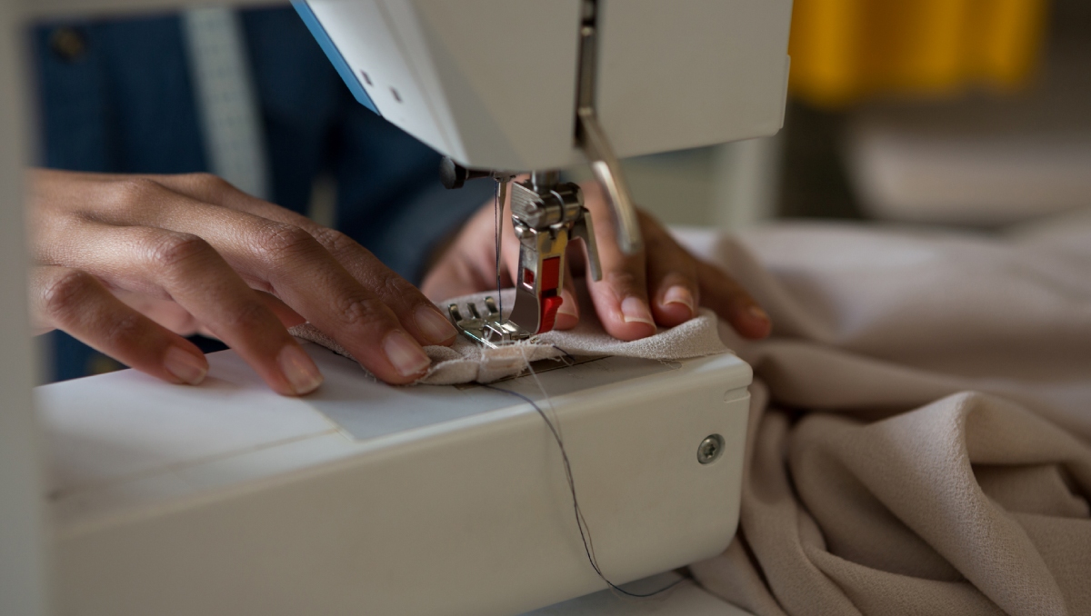 close up of hands using sewing machine to make wings feminine hygiene kits